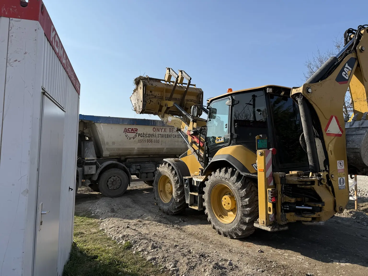 Nakladač pri nakladaní zeminy do nákladného vozidla
